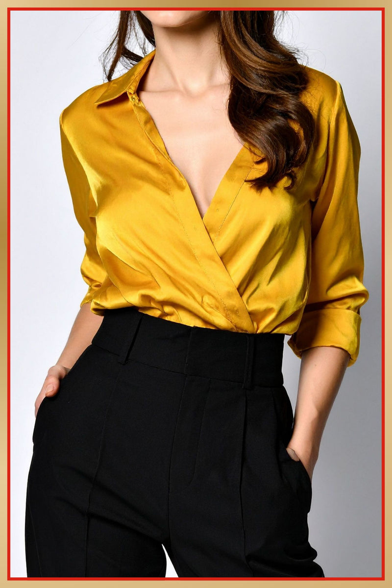 Yellow satin blouse with a deep neckline worn by a person on a plain background